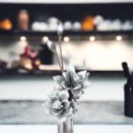 Graue Blumen in Vase vor unscharfem Hintergrund.
