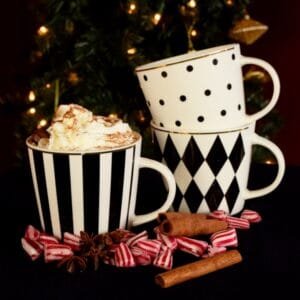 Drei Tassen mit Weihnachtsdekor, Zimt und Zuckerstangen.